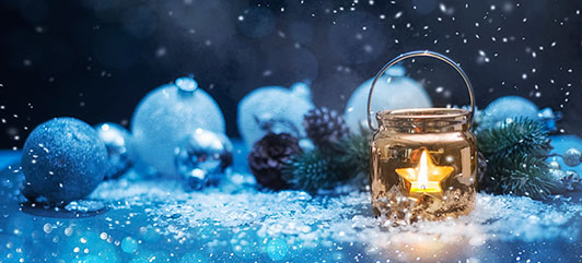 A star-shaped light that is inside a jar lit up with Christmas ornaments and a snowy background