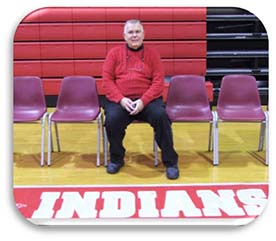 Mr. Ford sitting in a chair on a basketball court sideline.
