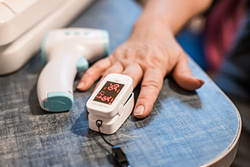 Patient with their hand resting on a table and a finger in a blood pressure testing device